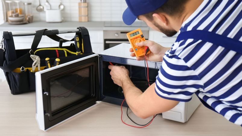 young electrician fixing microwave